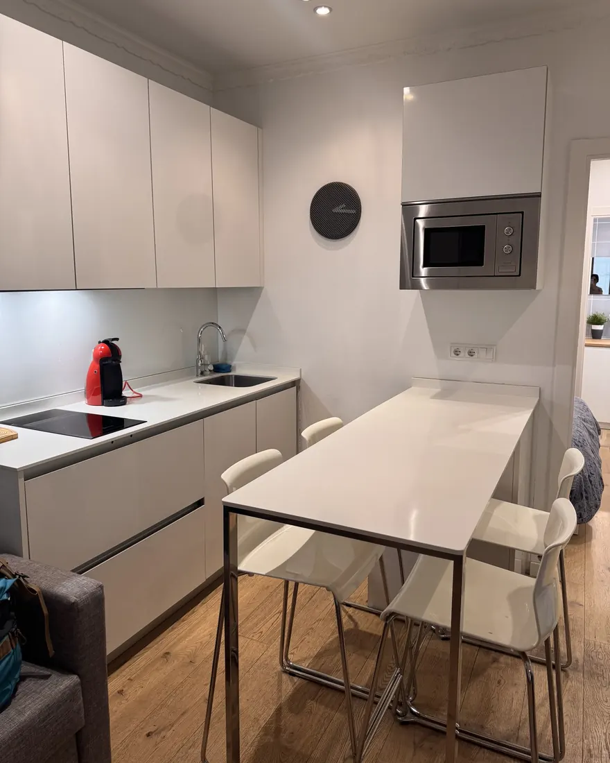 Cocina blanca con la encimera recogida y la mesa alta limpia