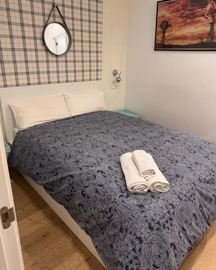 Dormitorio con la cama hecha y toallas dobladas encima