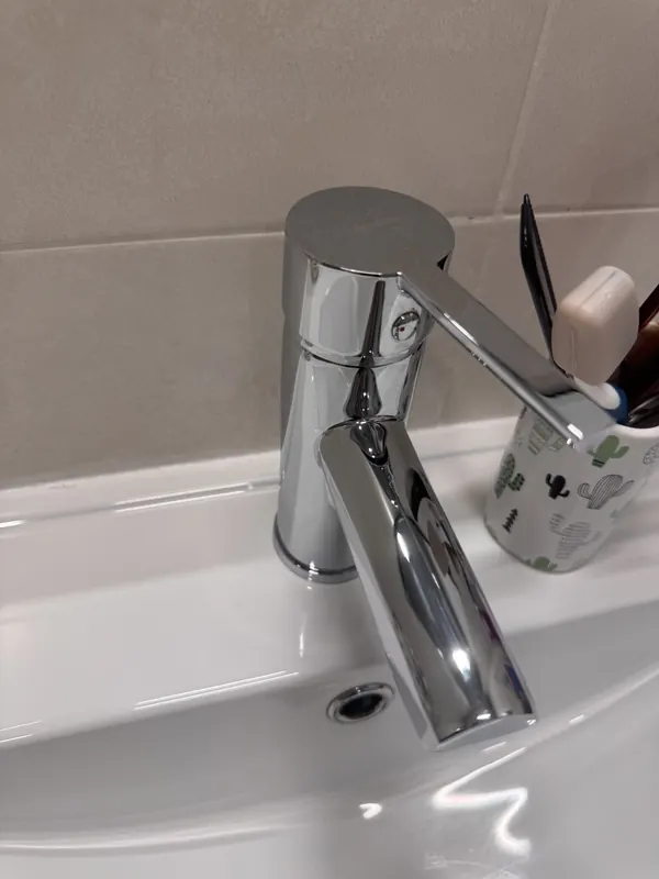 Grifo cromado brillante sobre un lavabo blanco